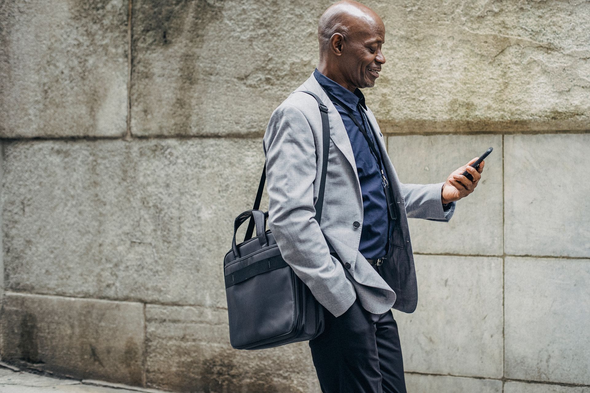 Smiling businessman in urban setting using smartphone, conveys success and connectivity.