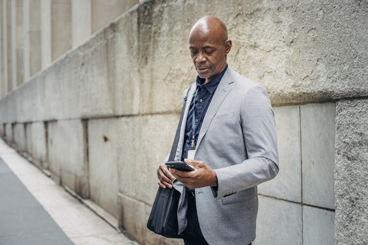 Focused African American Executive Browsing Internet On Sidewalk