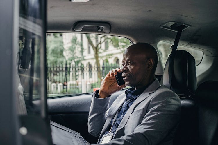 Serious Black Man Speaking On Smartphone In Car