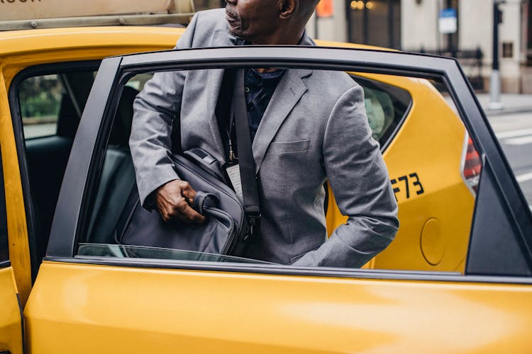 Crop Black Man Sitting In Taxi Car Parked On Street