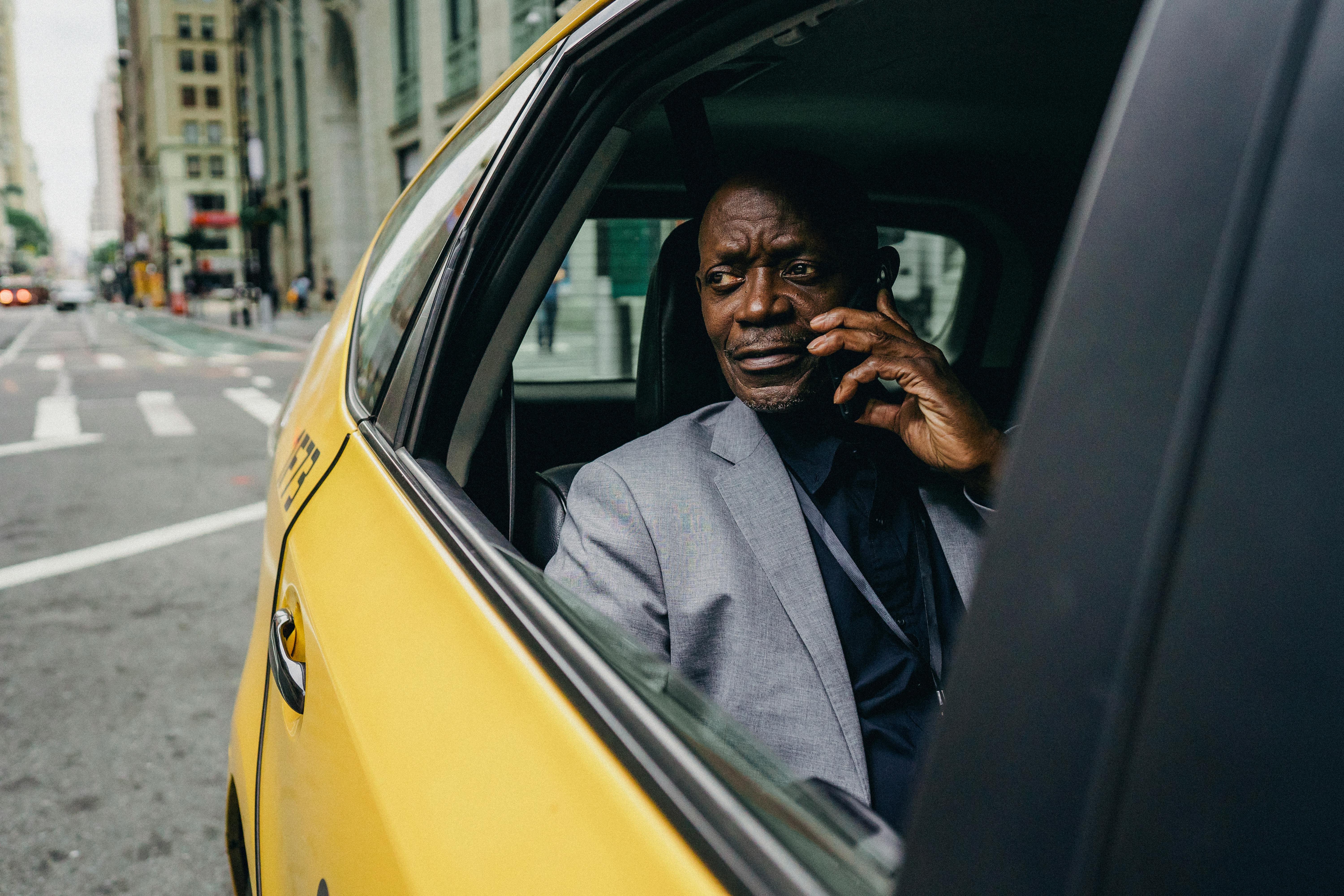 thoughtful black man riding taxi and talking on phone