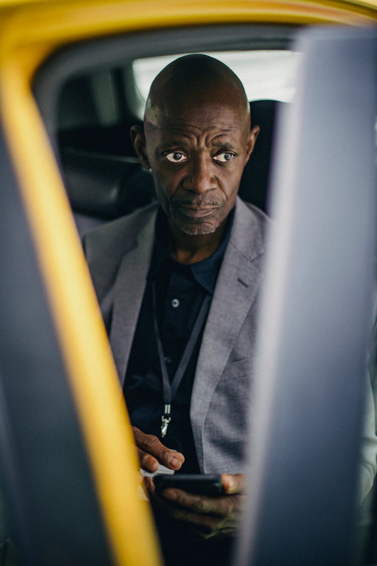 Pondering Black Businessman Using Smartphone In Car