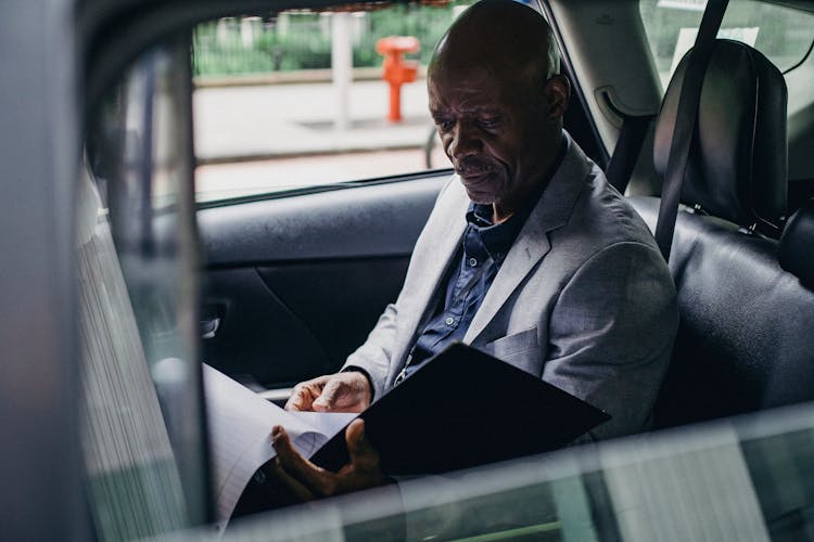 Concentrated Black Businessman Checking Documents In Car