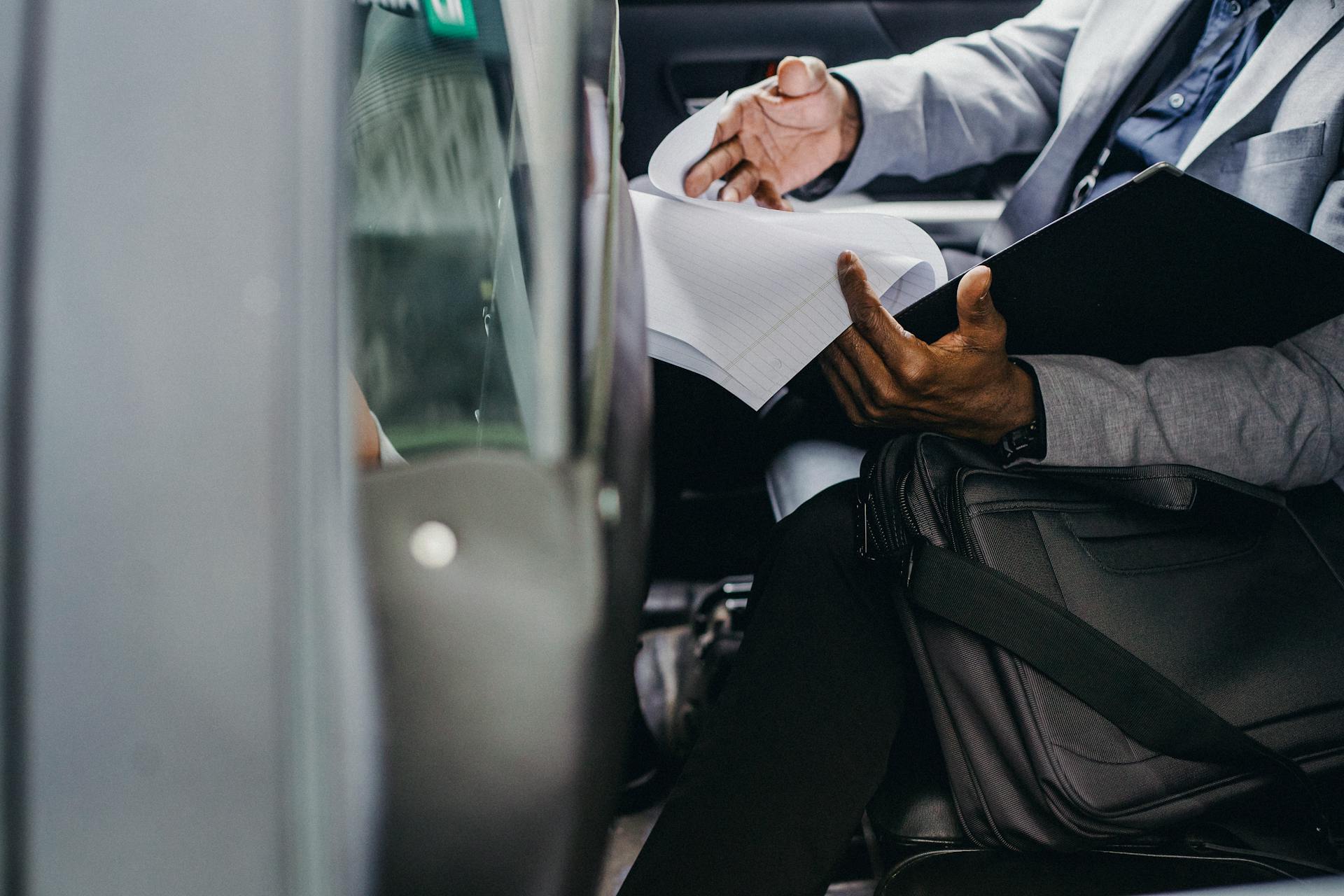 Businessman reviewing documents inside a vehicle, depicting focus and professionalism.