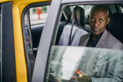 Middle aged African American male in business suit looking at camera while sitting in yellow automobile