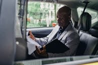 Focused black responsible man working with papers in car