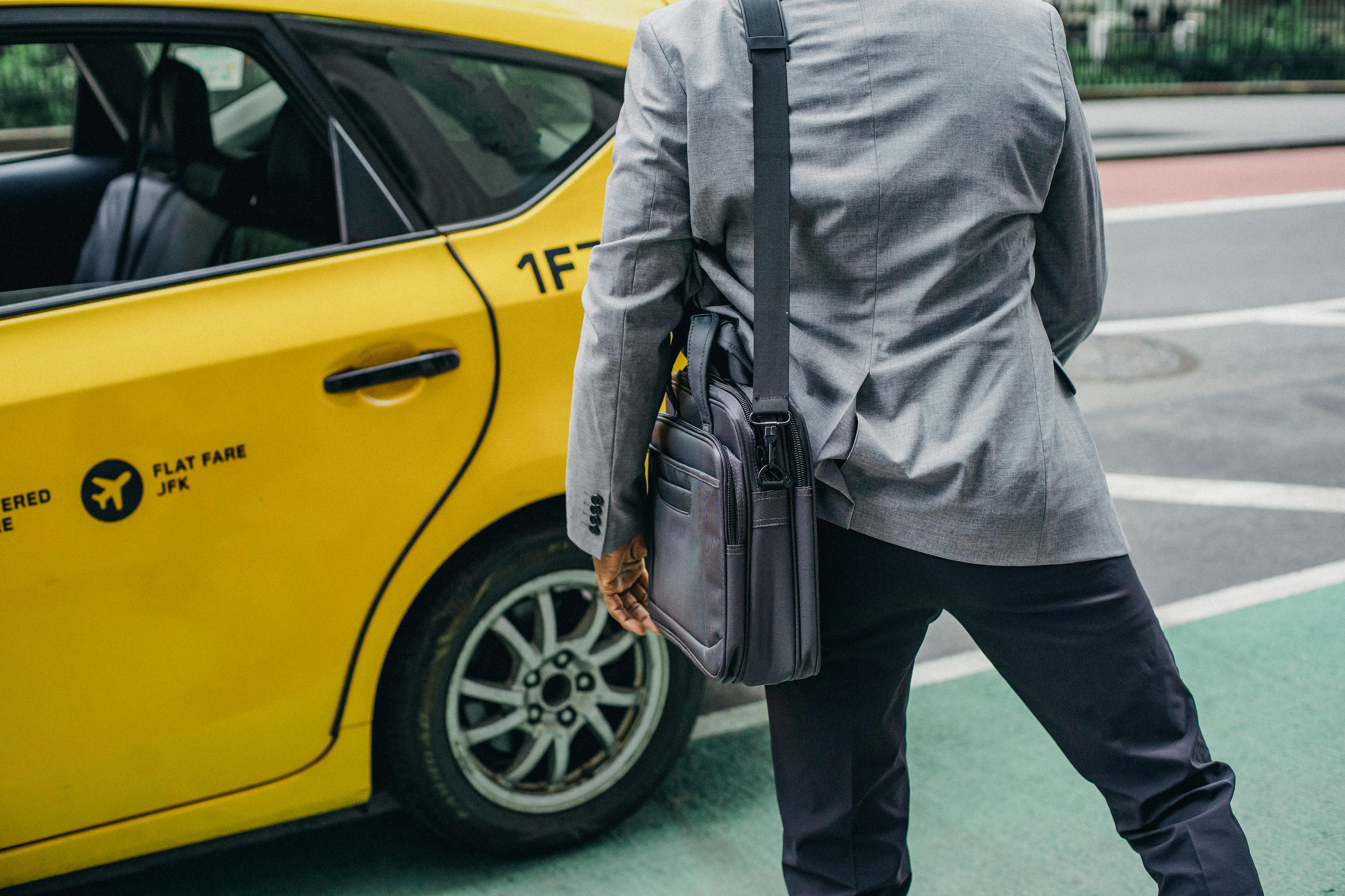 man in official outfit and bag near taxi