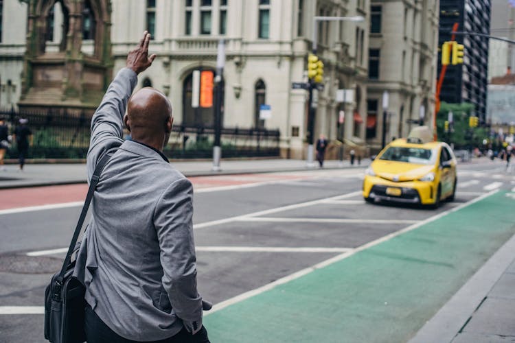 Black Man In Business Suit Catching Bright Yellow Taxi