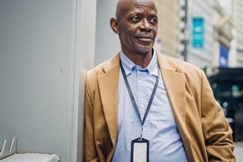 Middle aged African American male in coat looking away on blurred background of building