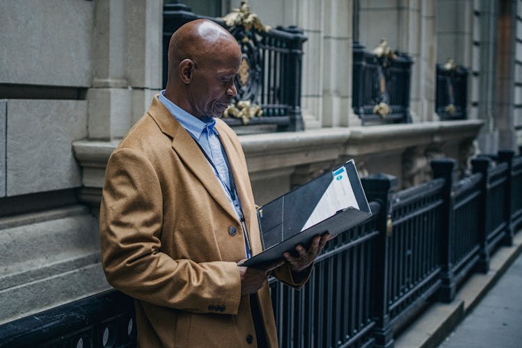 Experienced Black Lawyer Reading Documents On Street