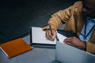 Crop ethnic businessman taking note on paper sheet at table