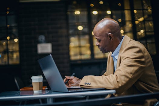 A businessman working on a laptop in a cozy cafe, focused and determined.