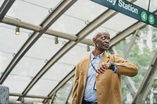 Пунктуальный черный мужчина проверяет время на наручных часах на станции метро