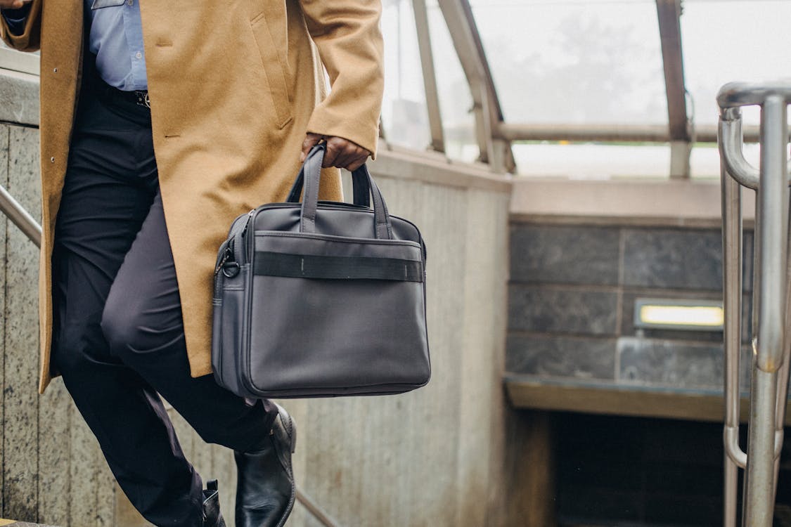 Free Crop unrecognizable African American businessman with briefcase going upstairs while leaving metro station Stock Photo