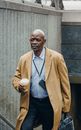 Contemplative black businessman standing with takeaway coffee near metro entrance