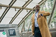 Pondering black businessman looking at wristwatch near subway