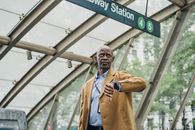 Pondering black businessman checking time on wristwatch near subway station