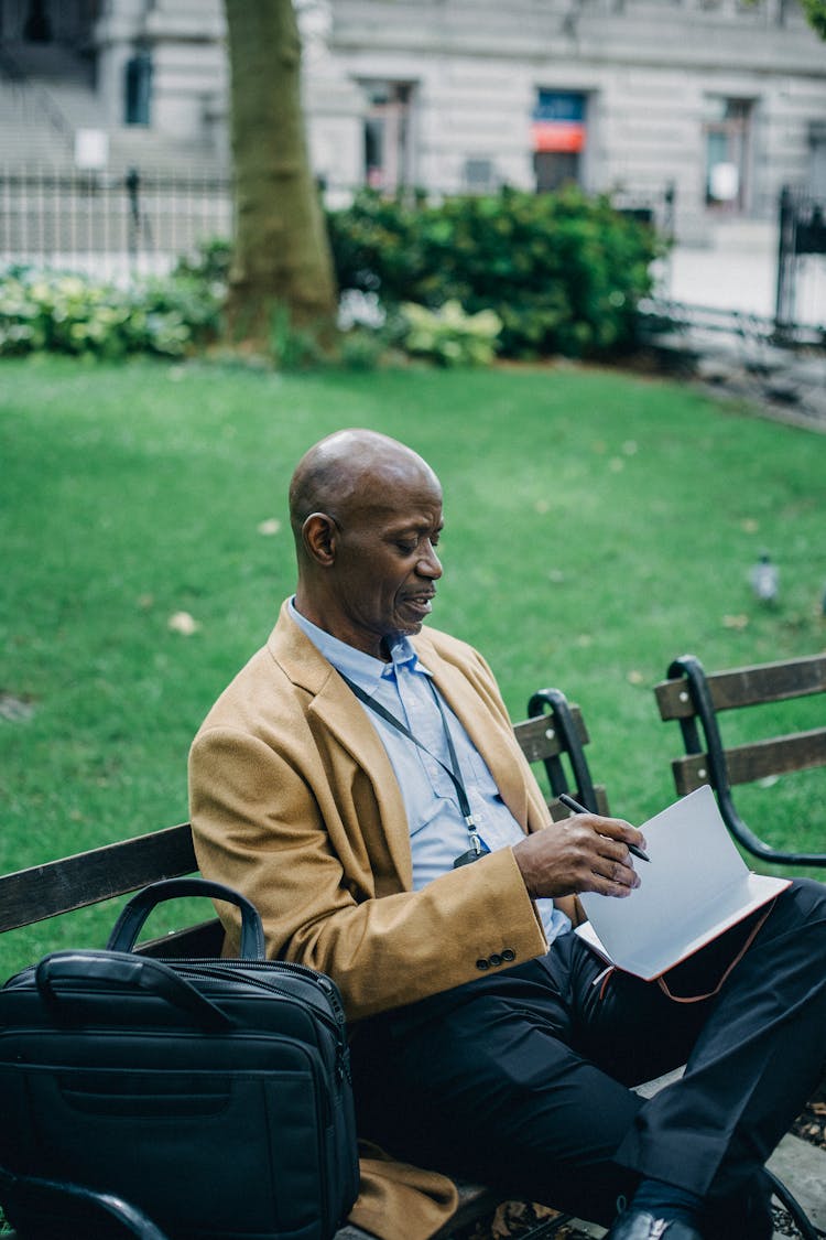 Stylish Black Businessman With Paper On Urban Bench