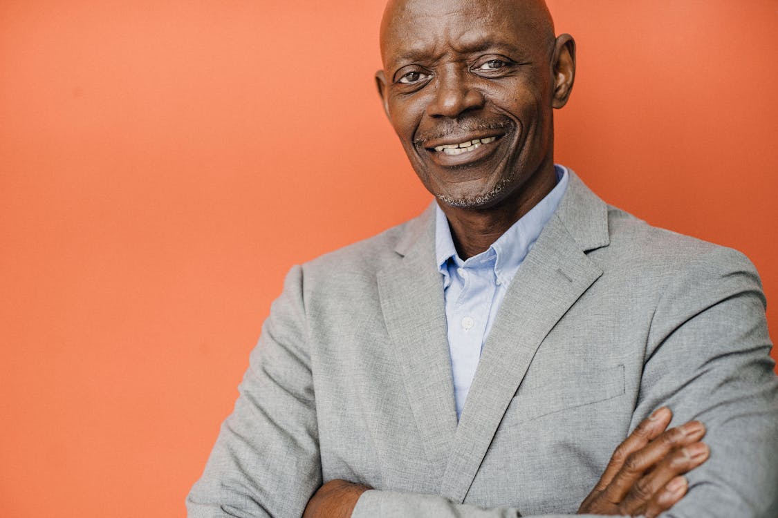 Free Crop glad middle aged male entrepreneur in formal apparel with folded arms looking at camera with toothy smile Stock Photo