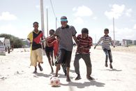 A group of Somali children playing soccer on a sunny day, showcasing joy and friendship.