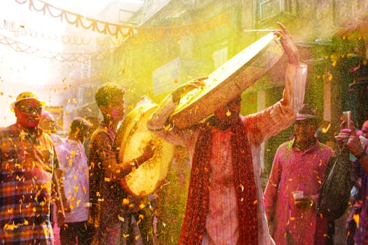 Dynamic street scene of Holi festival in India with people playing drums and throwing colored powders.