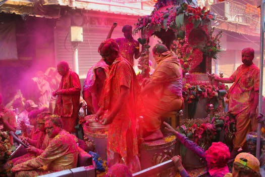 Colorful Holi celebration with people covered in powders in a vibrant street parade in India.
