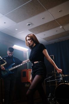 Dynamic live music scene featuring female singer and band in a rehearsal studio.