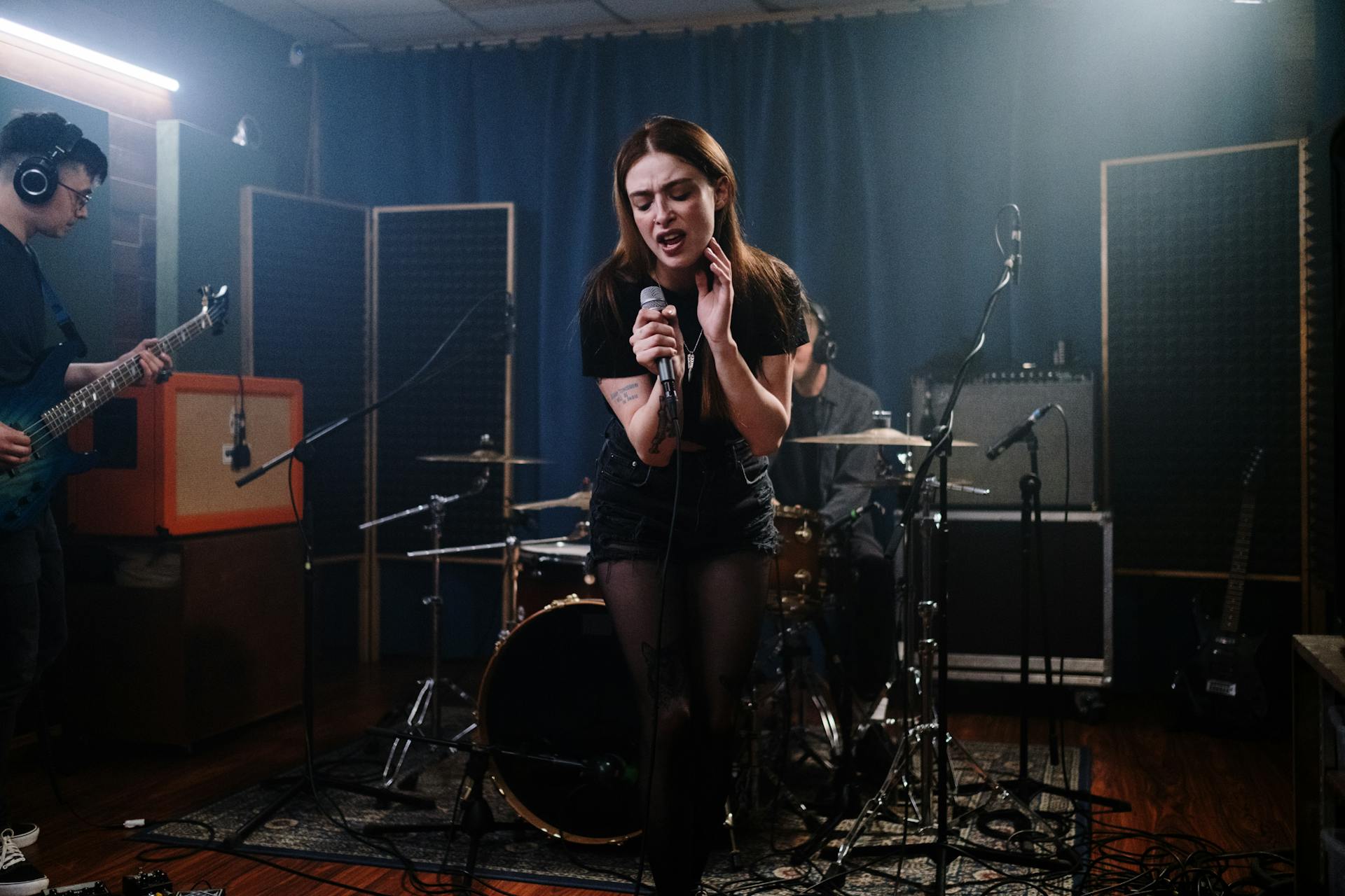 Energetic female singer performing with a band in a studio environment.