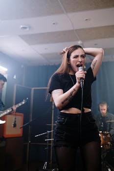 Dynamic scene of a tattooed female singer passionately performing with a music band indoors.