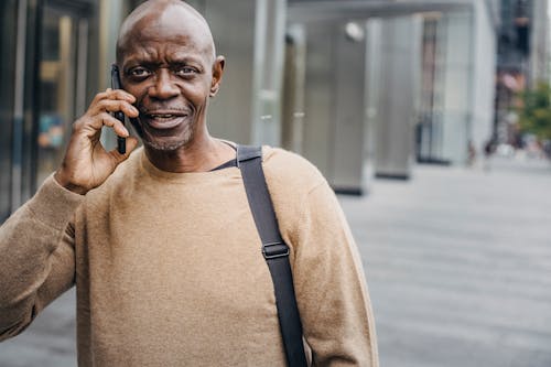 Bald black man talking on smartphone on street