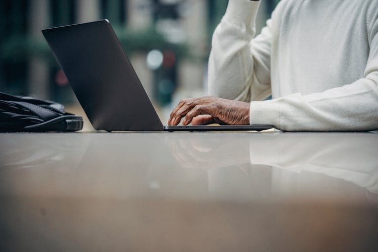 Unrecognizable African American Man Using Laptop In Street Cafe