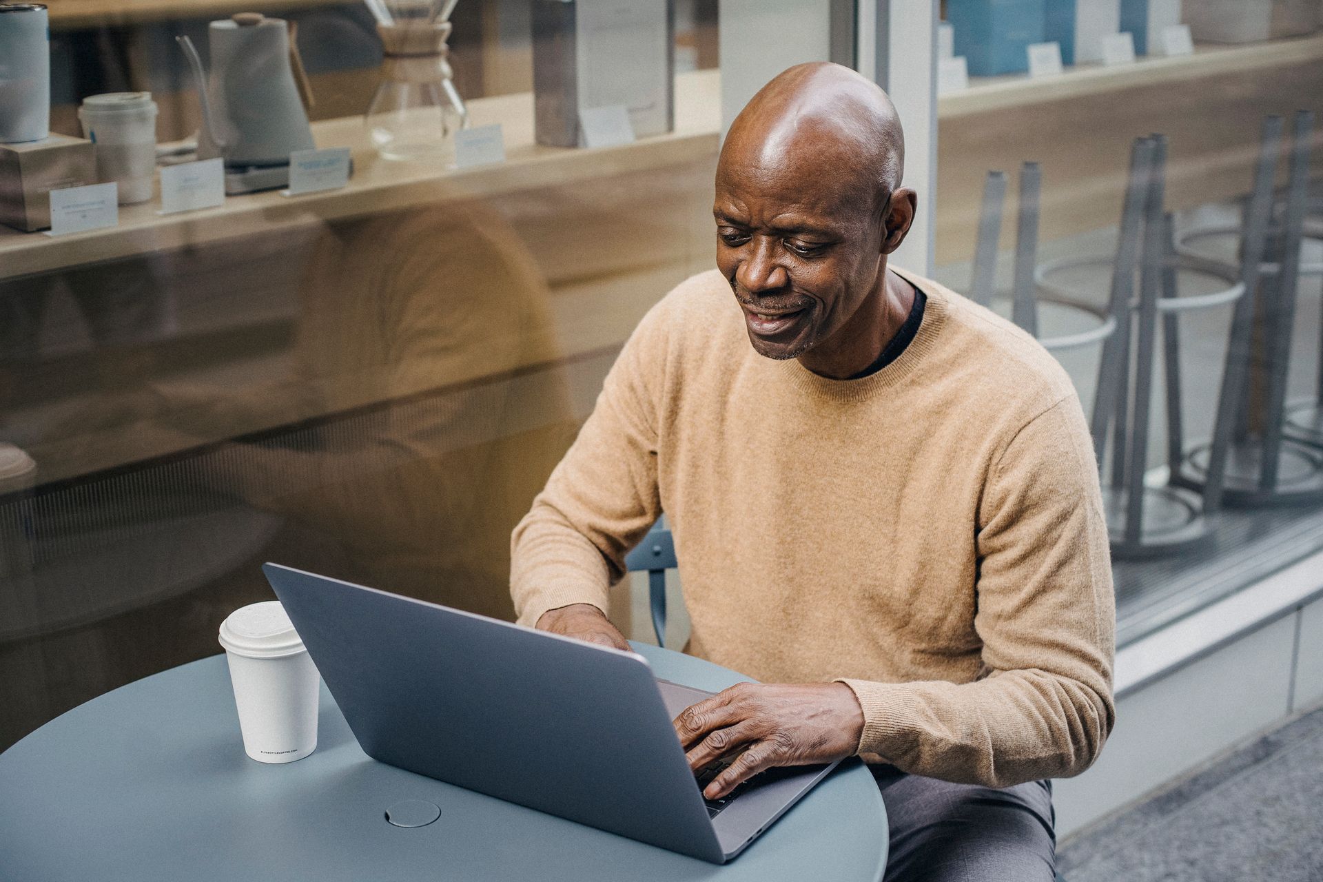 A bald man in a café using a laptop, conveying remote work lifestyle.