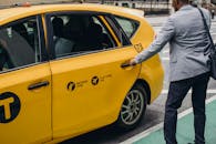 一位城市商人打开繁忙街道上的黄色出租车门，展现了现代通勤方式