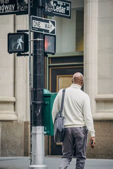 白天，一位身穿正式服装的匿名非裔美国男性在现代城区的人行横道上行走
