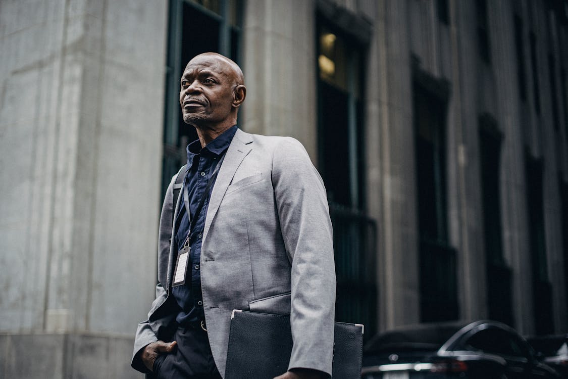 Confident black businessman standing against modern building in urban street