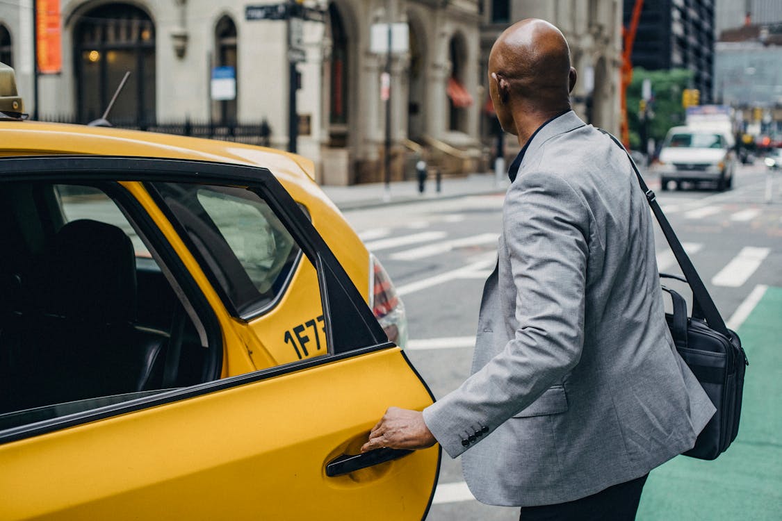 Faceless black man opening taxi door on busy street · Free Stock Photo