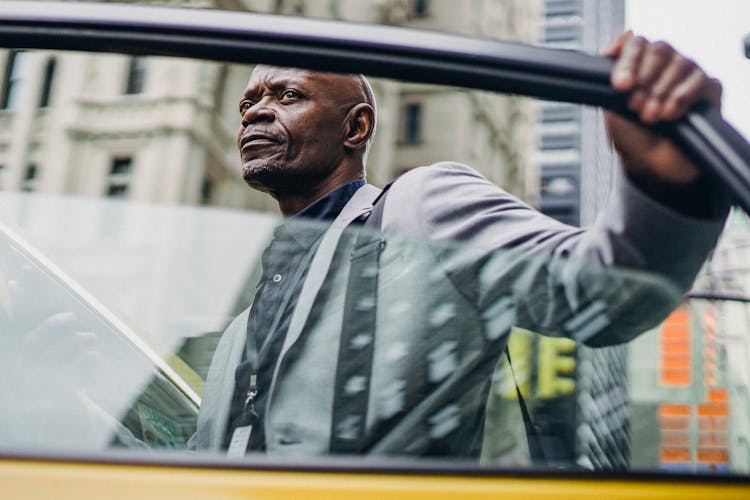 Serious Black Businessman Opening Taxi Door