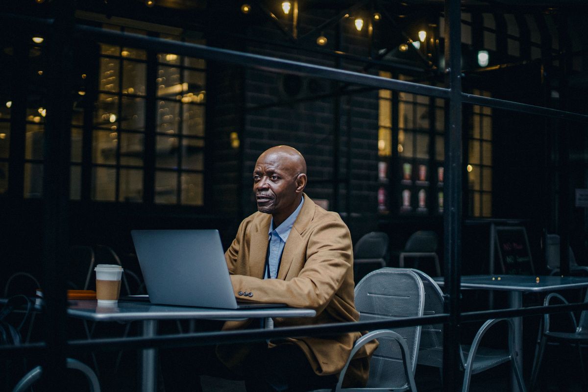 Person working on a laptop in a warm cafe interior — photo by Ono Kosuki on Pexels