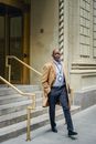 Full body respectable adult African American businessman in stylish coat leaving contemporary business center and walking towards camera