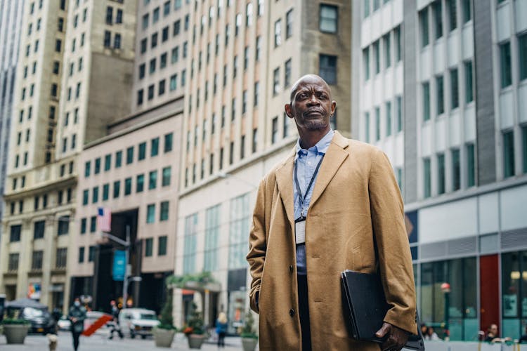 Masculine Black Office Employee Against Multistage Buildings In City