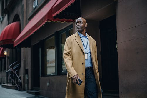 Well dressed black manager with badge on urban pavement