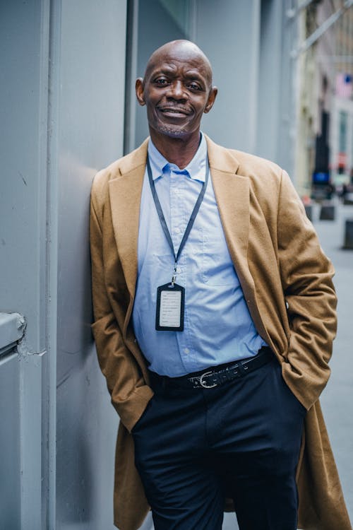 Smiling confident black manager with badge on city street