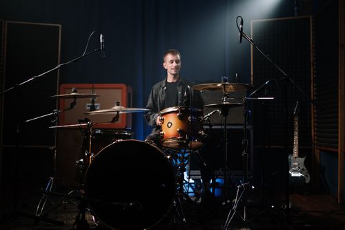 Free A solo drummer playing passionately under stage lights in a music studio. Stock Photo