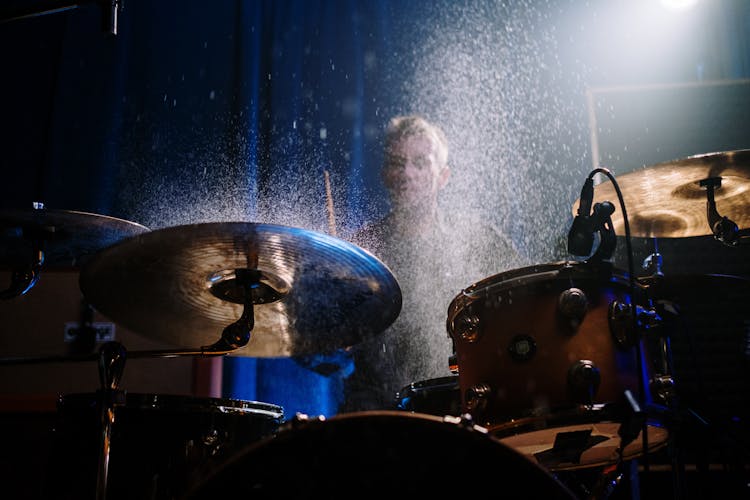 Man Playing The Drums In A Dark Room