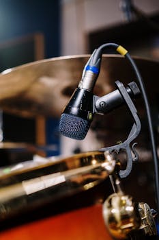 Detailed close-up of a microphone attached to a drum set in a music studio.