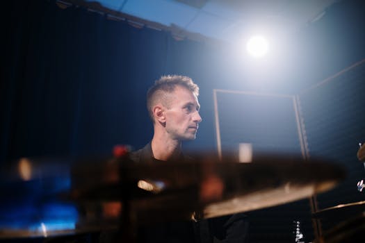 A portrait of a drummer in a studio setting with spotlight lighting, capturing a creative atmosphere.