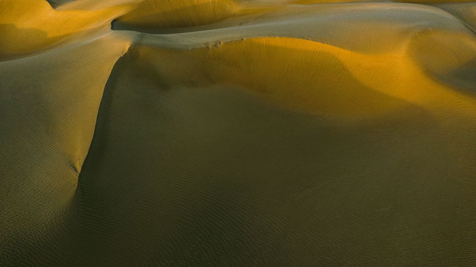 A breathtaking aerial view showcasing the golden dunes of Xinjiang's vast desert landscape.