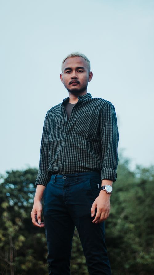 Free Low angle shot of an adult Asian man standing outdoors in casual wear. Stock Photo