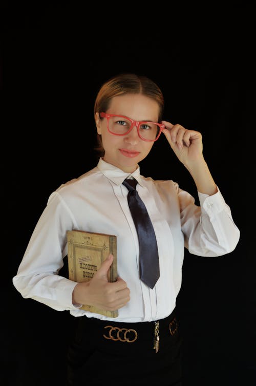 Young businesswoman putting on eyeglasses in studio