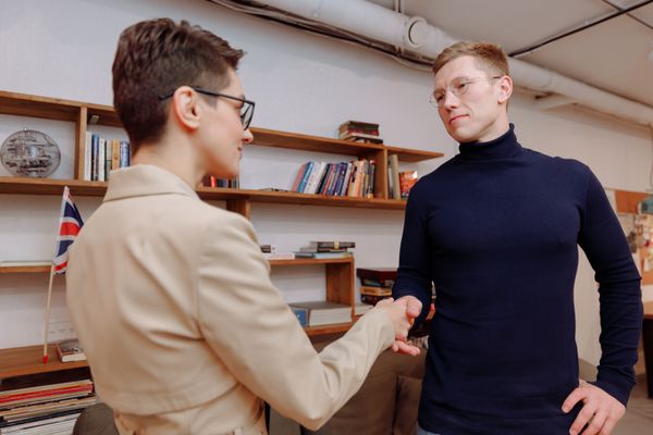 Two adults in a professional handshake indoors, fostering communication and connection.